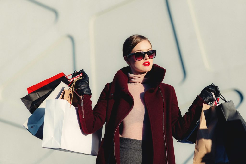 Stylish woman holding multiple shopping bags confidently.