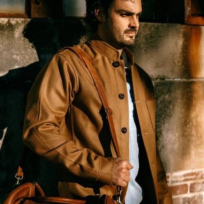 Man in brown jacket carrying leather bag